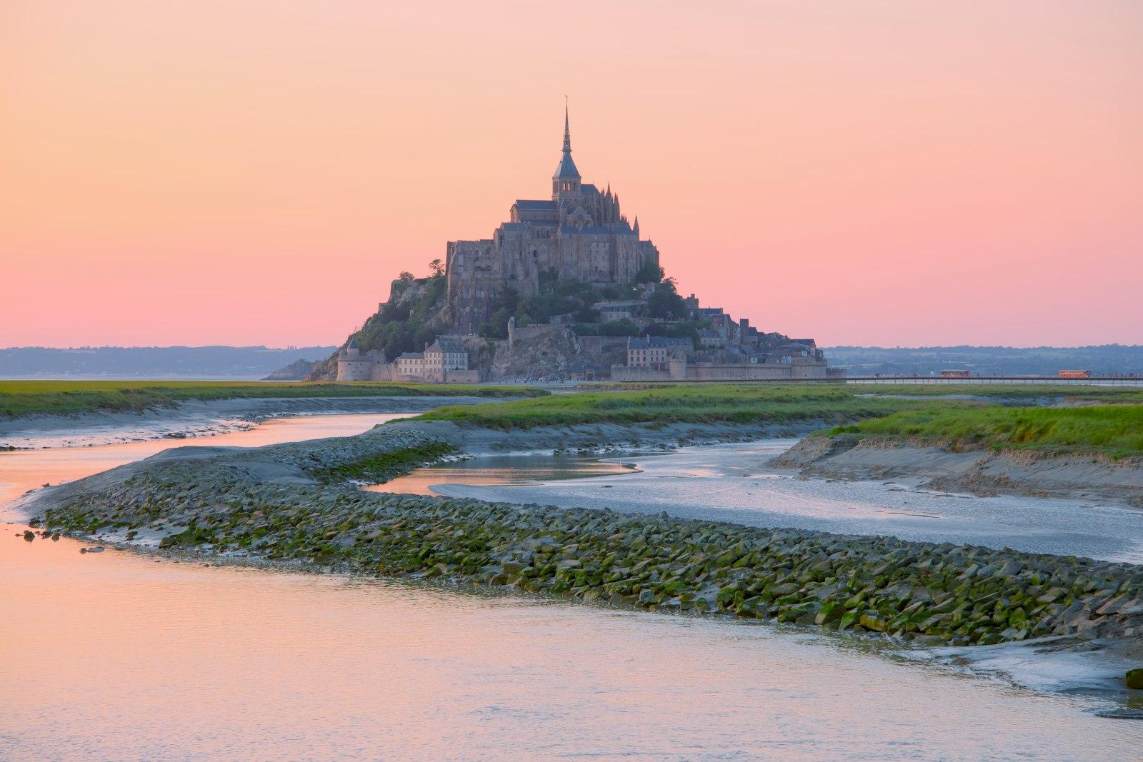 Mont Saint-Michel with the abbey crowning the rock, seen across the bay at dusk