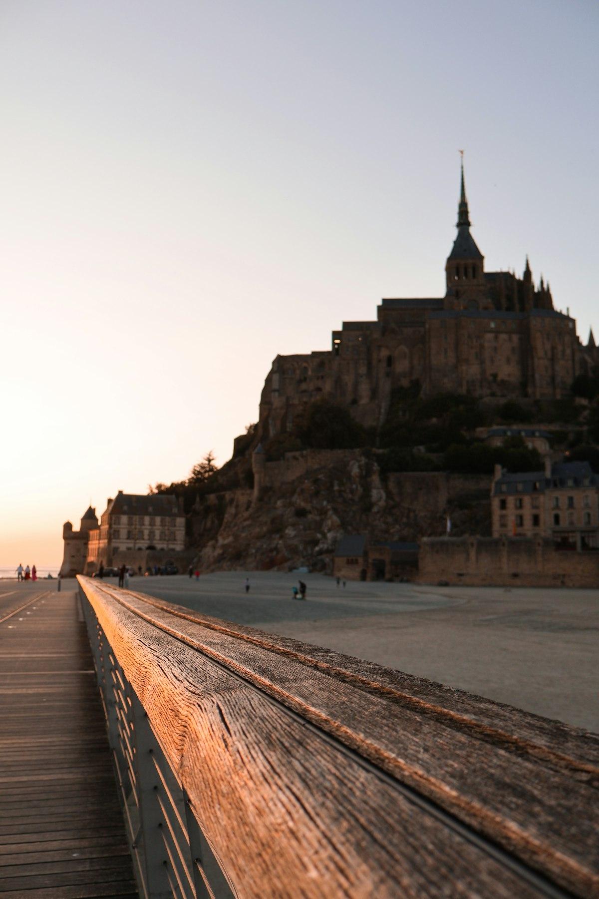 The wooden walkway of the pedestrian bridge leading to Mont Saint-Michel at sunset